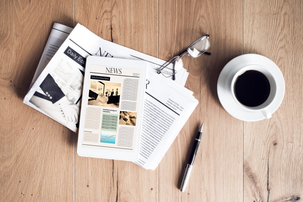 Eine Zeitung ein Tablet mit News und ein Kaffee auf dem Tisch