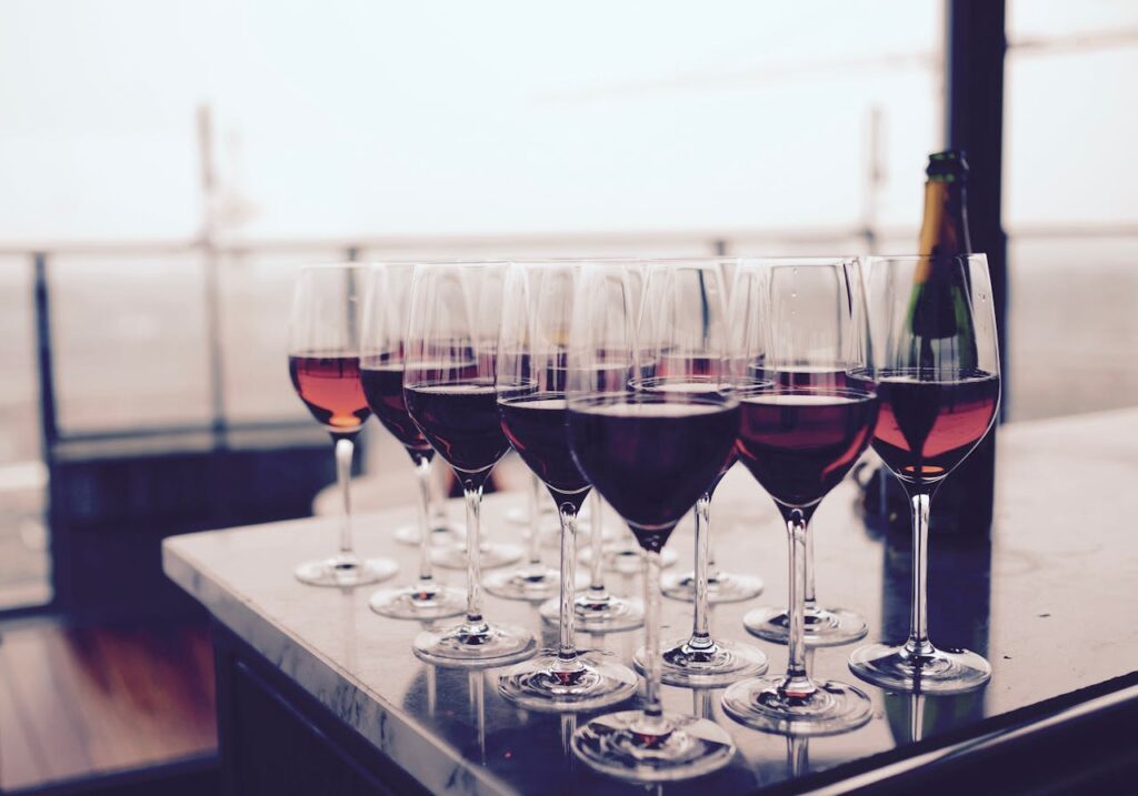 Mehrere Gläser Rotwein auf einem Tisch und einer Flsche im Hintergrund