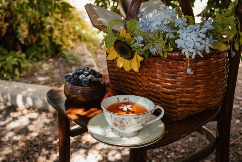 Ein Blumenkorb, Tasse Kaffee und Beeren auf einem Stuhl im Garten